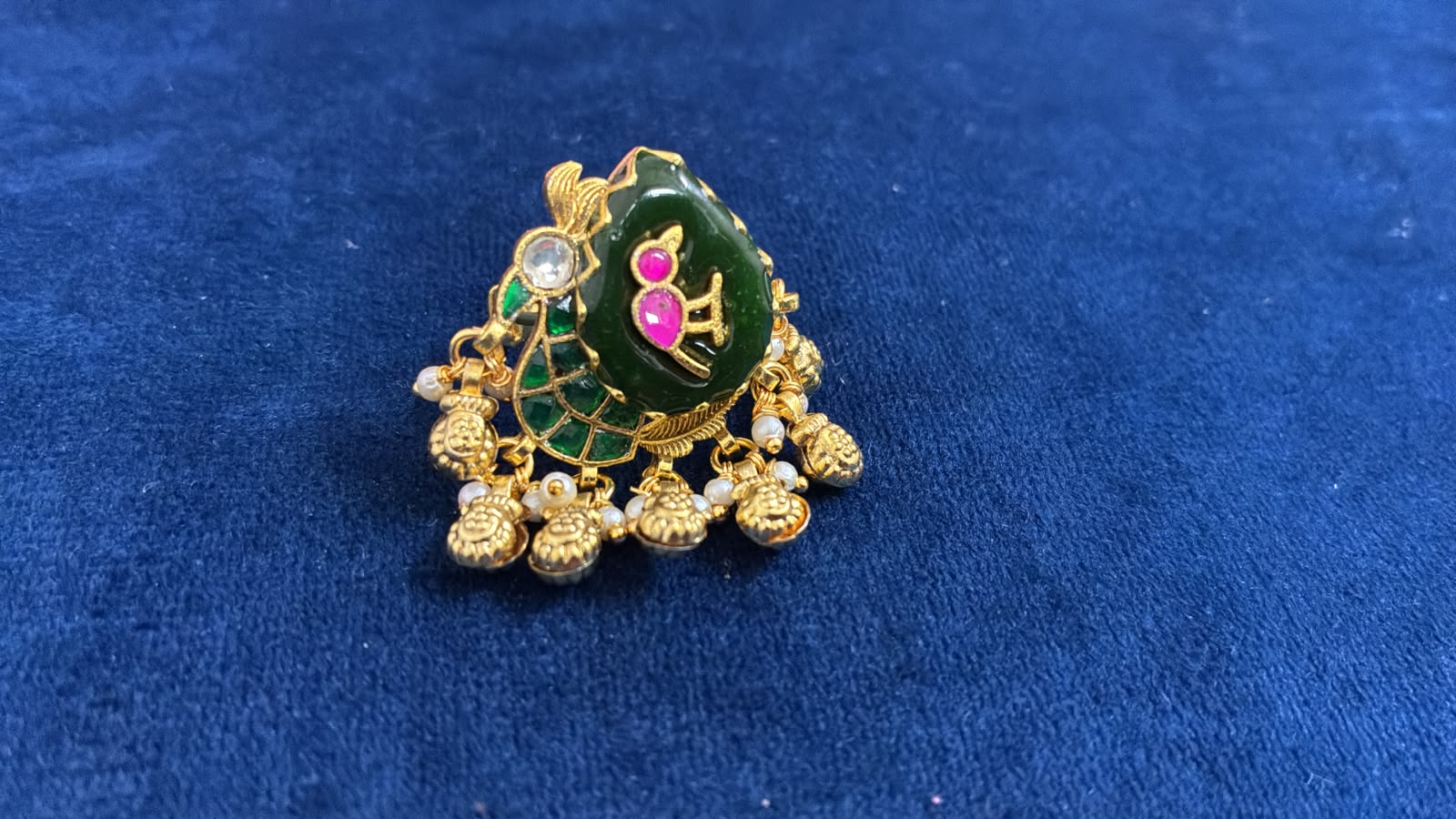 Gold parrot ring on a deep green ambi stone with flat-cut pink jadau work and a seed pearl fringe