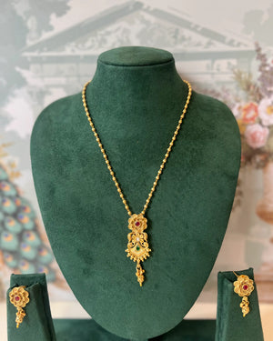 Gold necklace with floral pendant set with red and green stones, with matching drop earrings