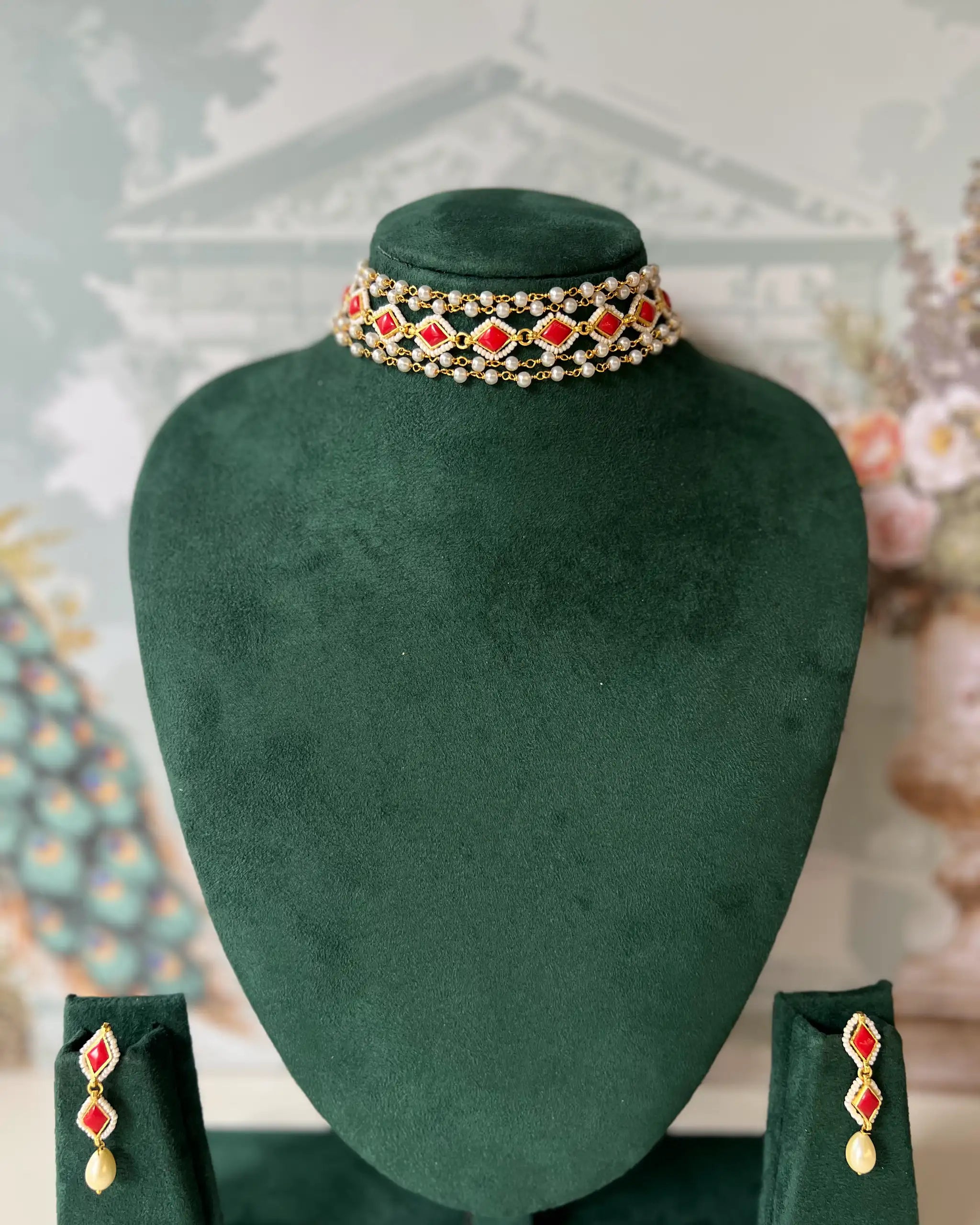 Gold-tone multi-strand choker with red kundan-style stones and pearl beading, with matching drop earrings