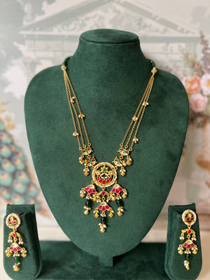 Ruby and emerald kundan necklace set with triple gold chains, pearl-bordered medallion, palmette fan drops and green bead drops with matching earrings