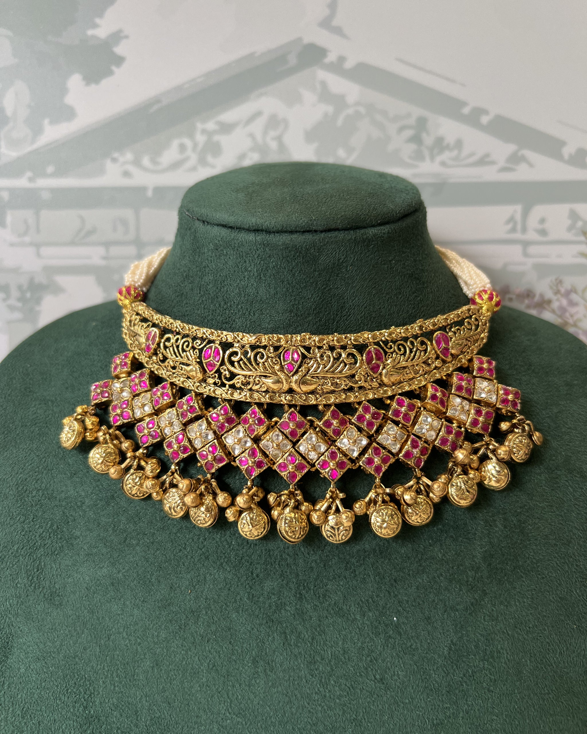 Close-up of antique gold peacock filigree choker with ruby and white kundan diamond jaali lattice and gold ghungroo drops